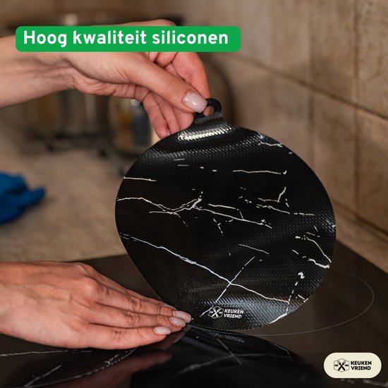 Hand plaatst een zwarte marmerlook inductiebeschermer van Keukenvriend op een kookplaat